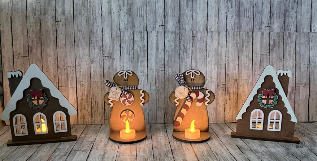 Lighted gingerbread village set, two houses and two gingerbread men with tea lights glowing