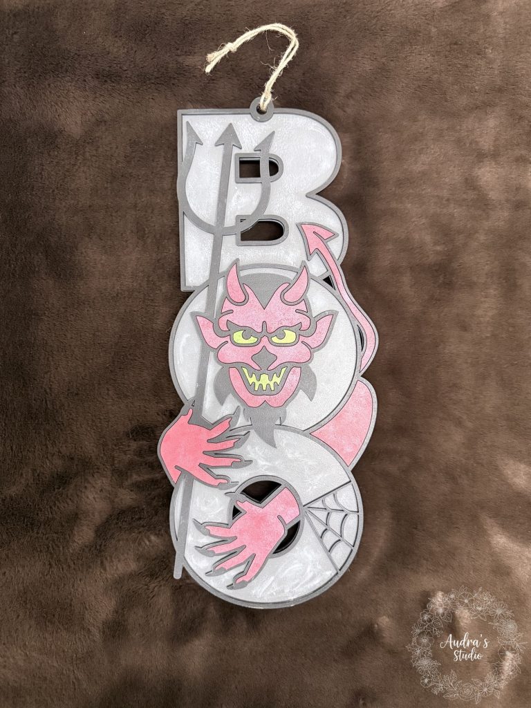 Grey and white layered wood BOO sign with a pink devil, hand painted, hanging by jute cord
